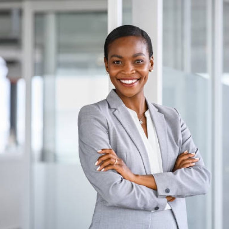 Portrait of mid adult successful black mature woman looking at camera with arms crossed. Smiling african american business woman standing in new office with copy space. Portrait of mature beautiful and confident businesswoman with big smile on her face.